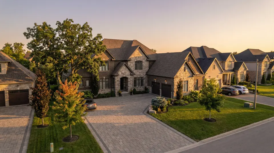 Aerial view of stone estate homes on a curved street at golden hour