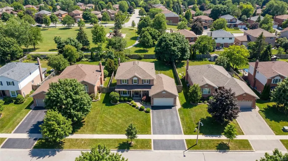Aerial view of a leafy suburban street with brick homes and a park beyond