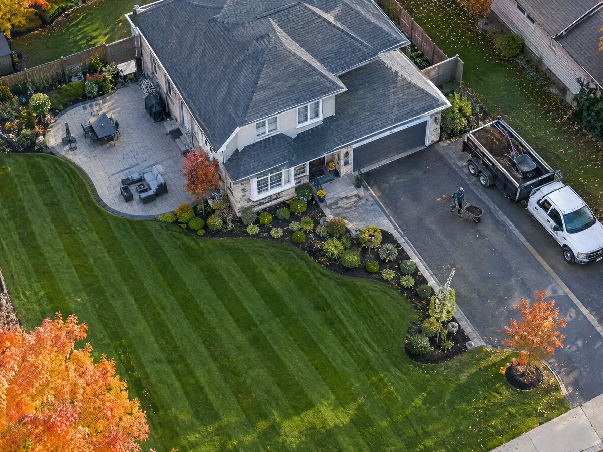 Drone photo of a striped lawn, new garden beds and patio with a work truck in the driveway