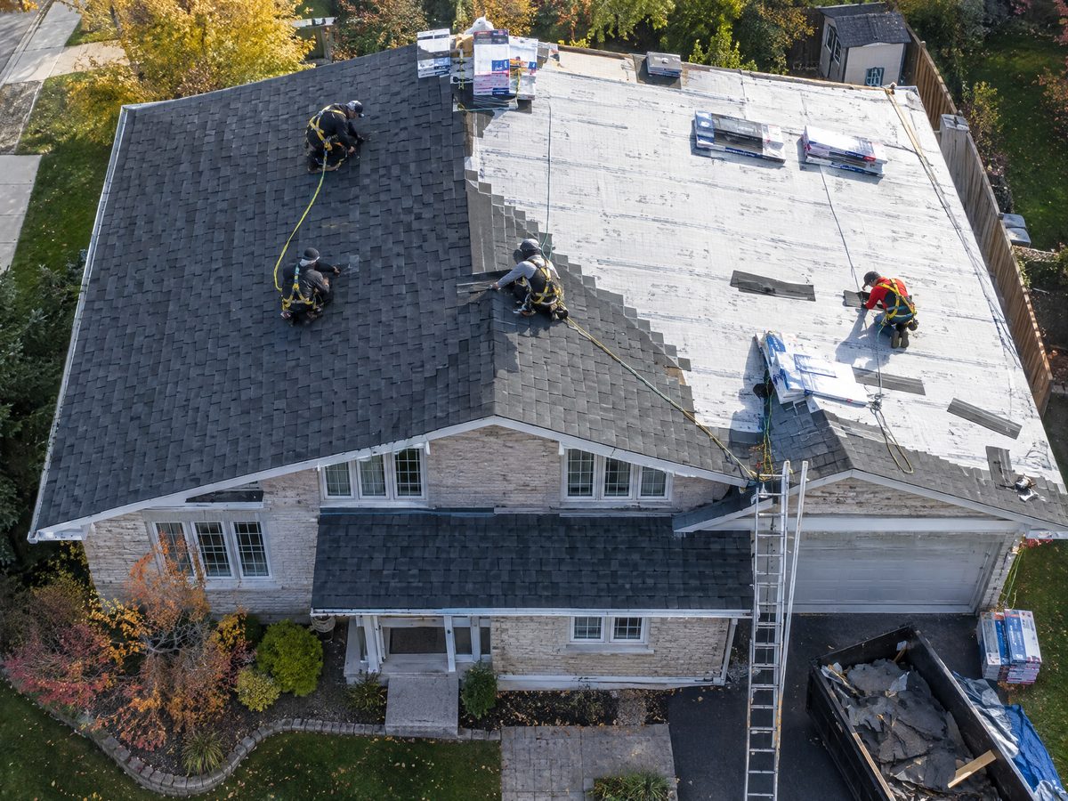 Aerial photo of roofers installing shingles on a two-storey home