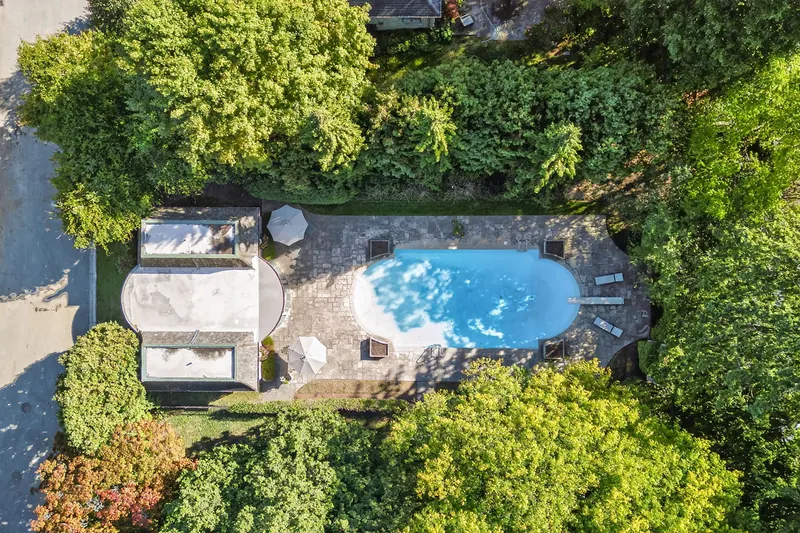 Top-down aerial of an estate pool among mature trees — London real estate photography by Estate Shutter