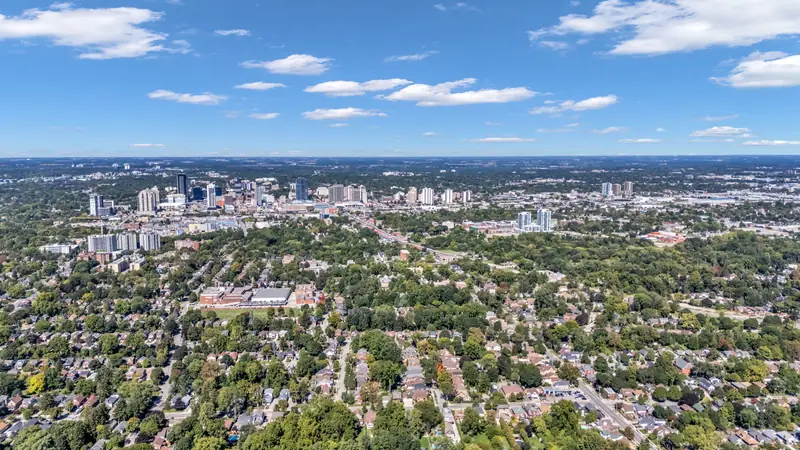 High aerial over London, Ontario neighbourhoods toward downtown — drone photo by Estate Shutter