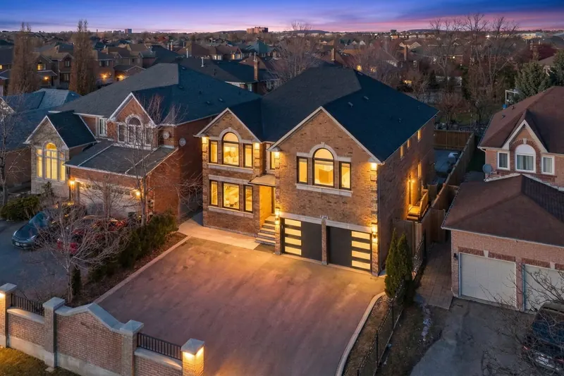 Twilight aerial of a brick home with the lights on — Mississauga real estate photography by Estate Shutter